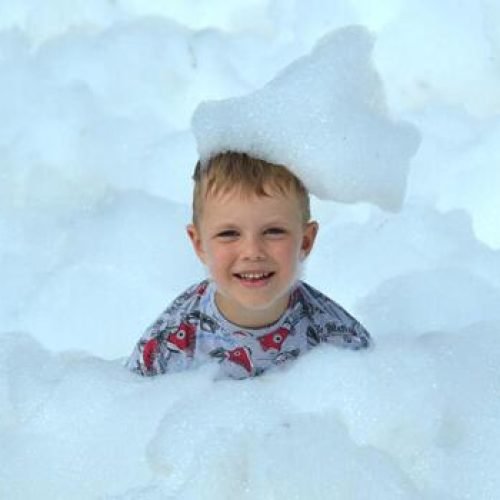 happy-little-boy-with-foam-on-his-head-in-wet-clothes-at-a-foam-party-photo